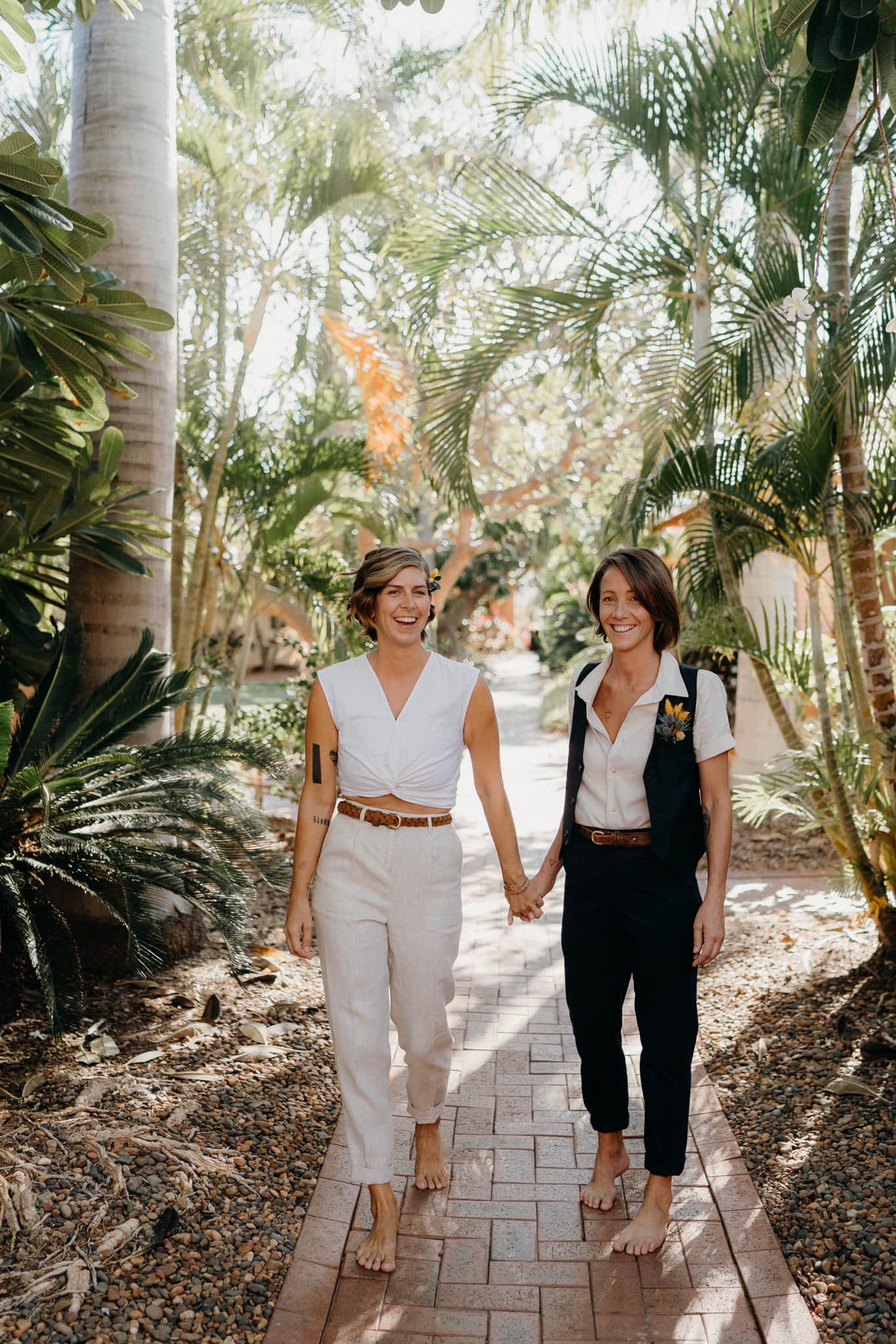 two young women hand in hand in resort garden at Broome elopement 