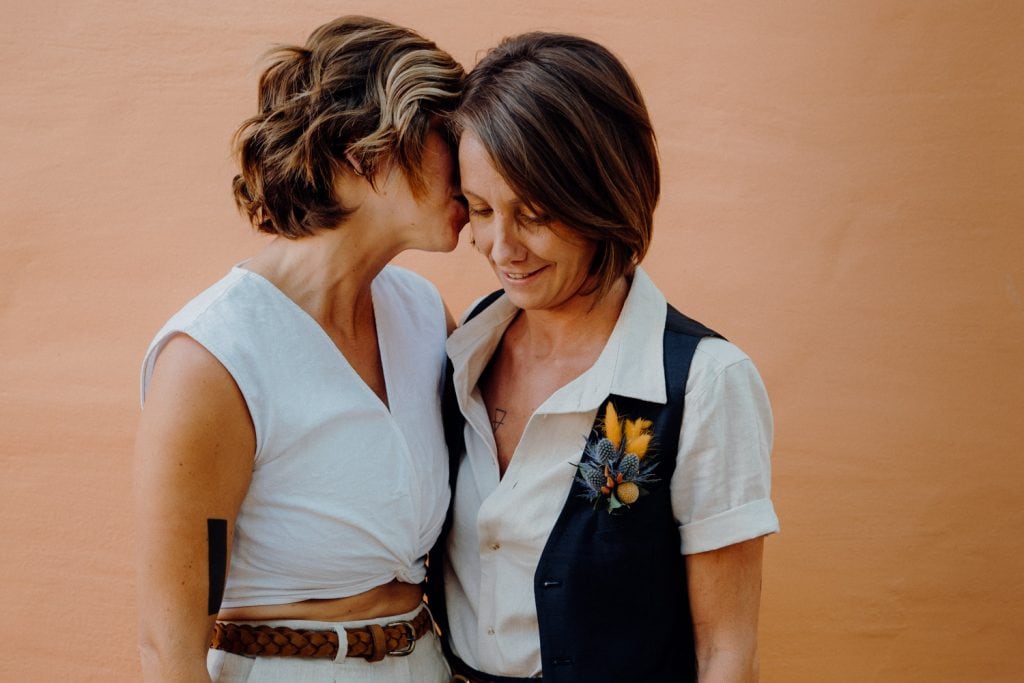 two women in front of orange wall at their Broome elopement