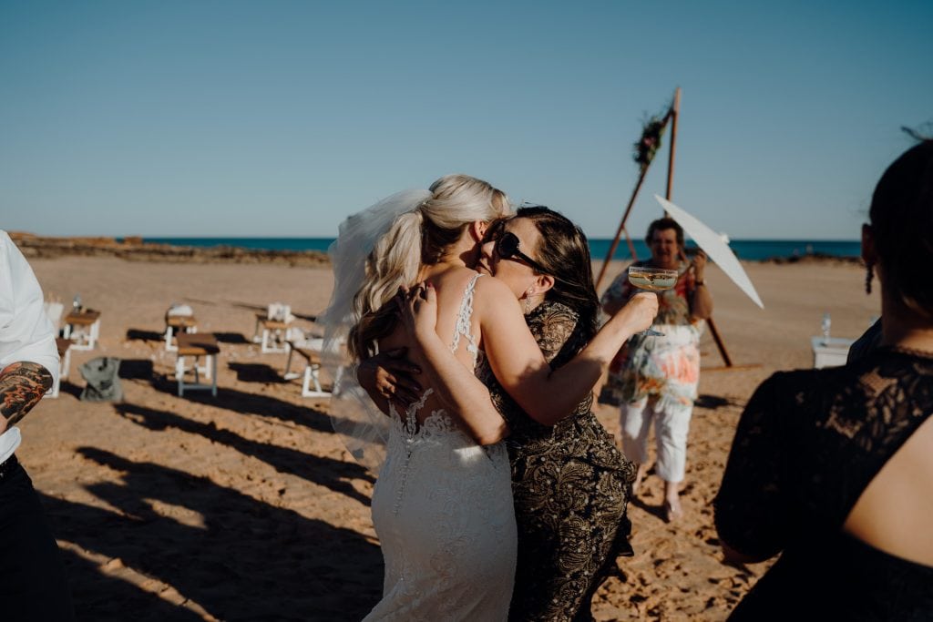 wedding guests embraces the bride in a big hug at her beach wedding