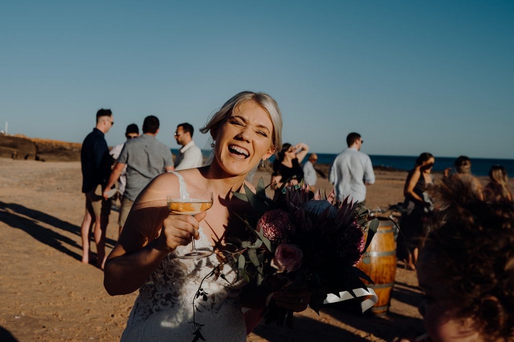 laughing bride with Champagne glass and flower bouquet