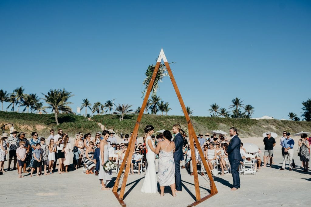 Cable Beach wedding ceremony in Broome with couple standing under wooden arbour