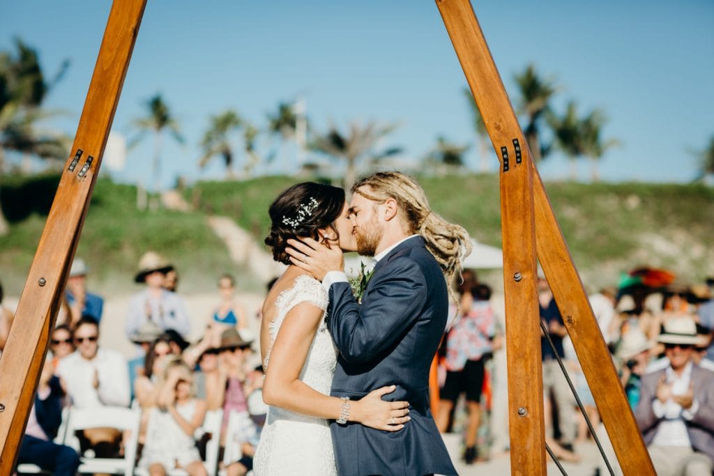freshly hitched couple kissing at beach wedding ceremony 