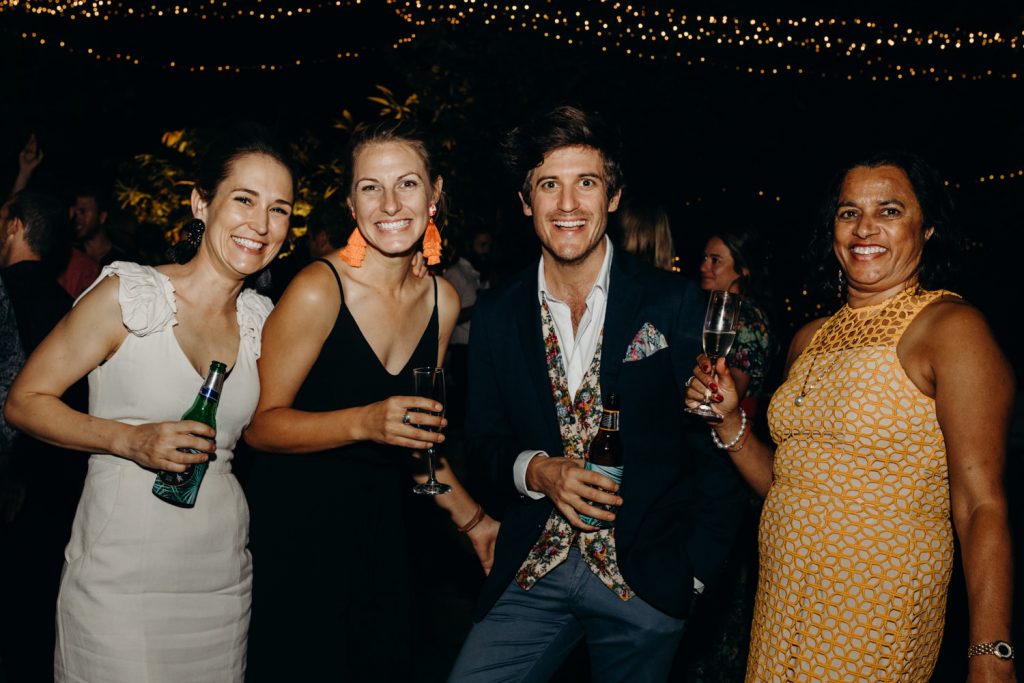 group of wedding guests smiling at the camera with drinks in their hands