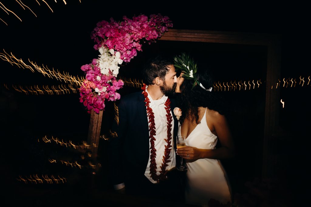 bride and groom kissing at the Broome wedding reception under an arch of bougainvillea