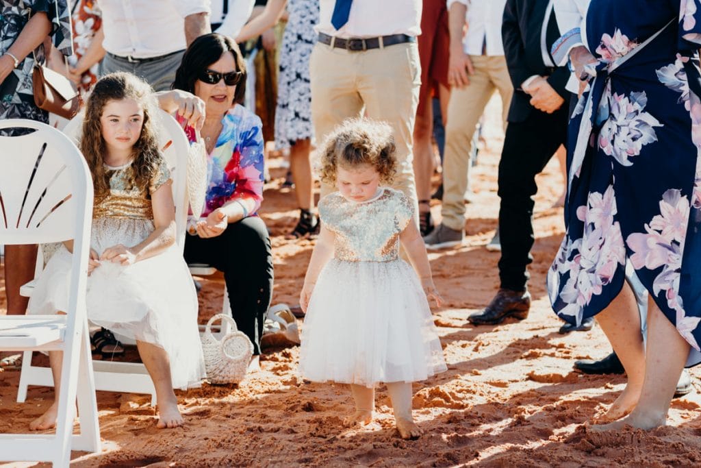 little girl in golden dress barefoot at beach wedding
