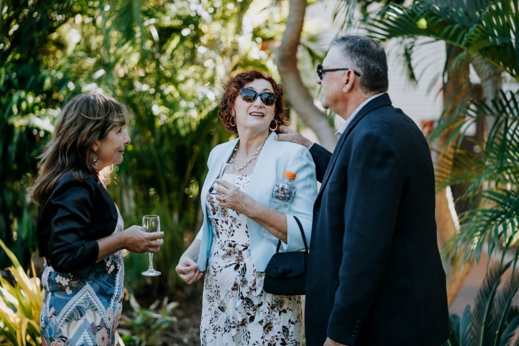 two women and one man chatting in tropical garden at wedding