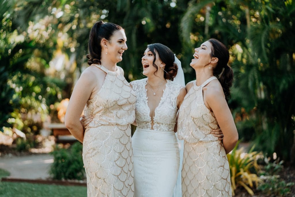 bride and her two bridesmaids laughing together in the tropical garden of the Cable Beach Club Resort