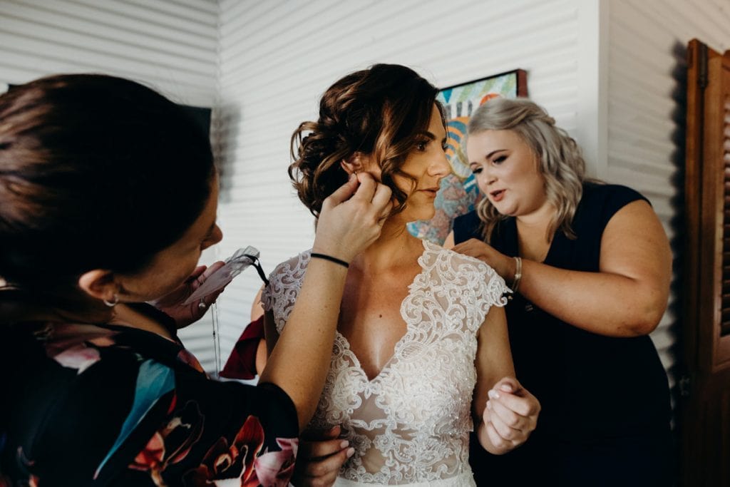 bride putting on jewellery with the help of her girlfriends