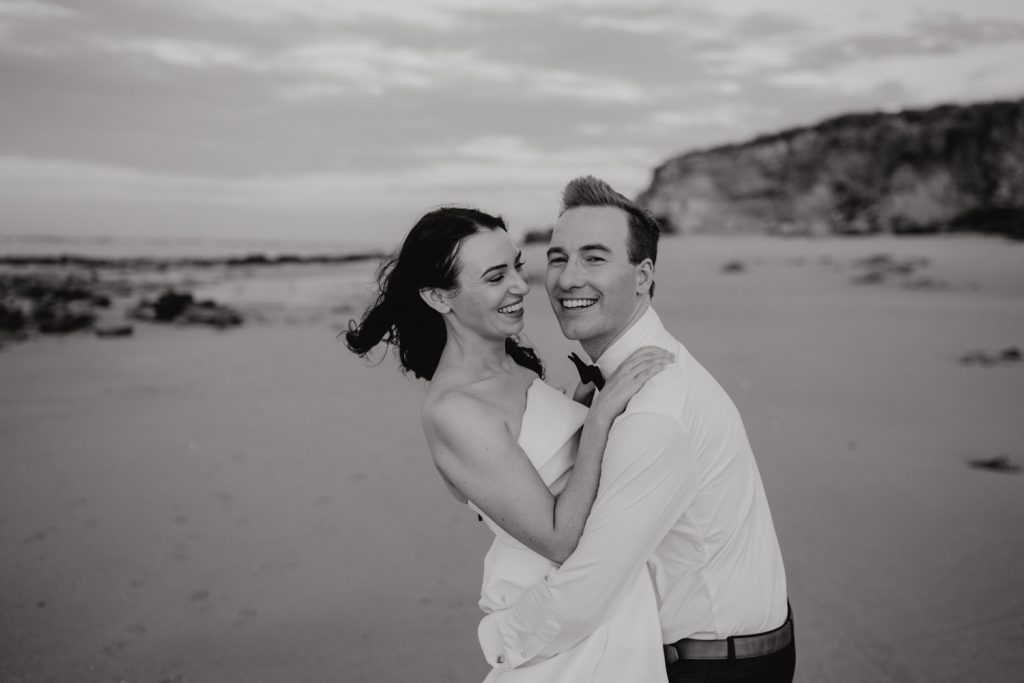 black and white shot of groom and his beautiful bride laughing and having a good time at Eco Beach