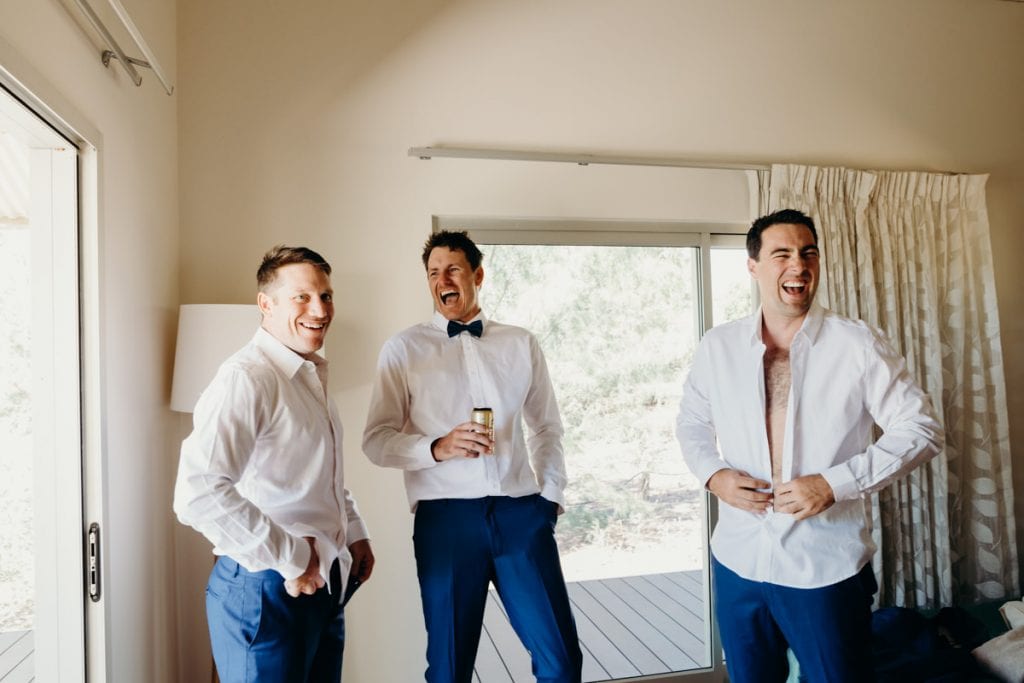 groom with two groomsmen laughing and drinking beer