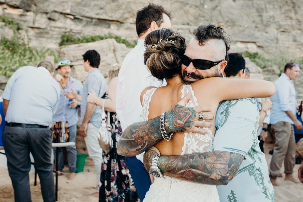 wedding guest with tattoos hugs bride