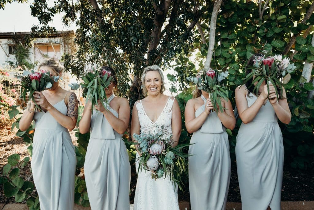 bride and bridesmaids standing in line with Broome Florist flower boquets