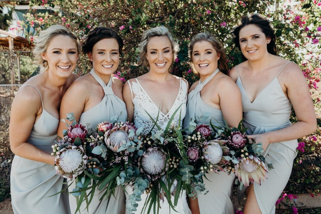 group photo of bride with her bridesmaids with Broome Florist flowers and bougainvillea in the background