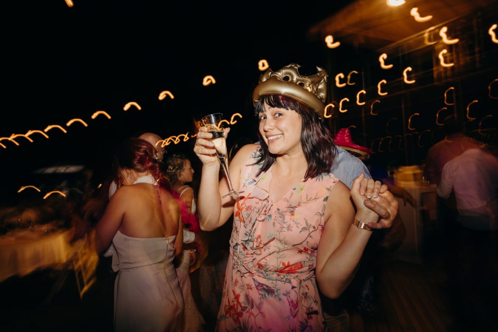 wedding guest on dance floor with glass of champagne in her hand
