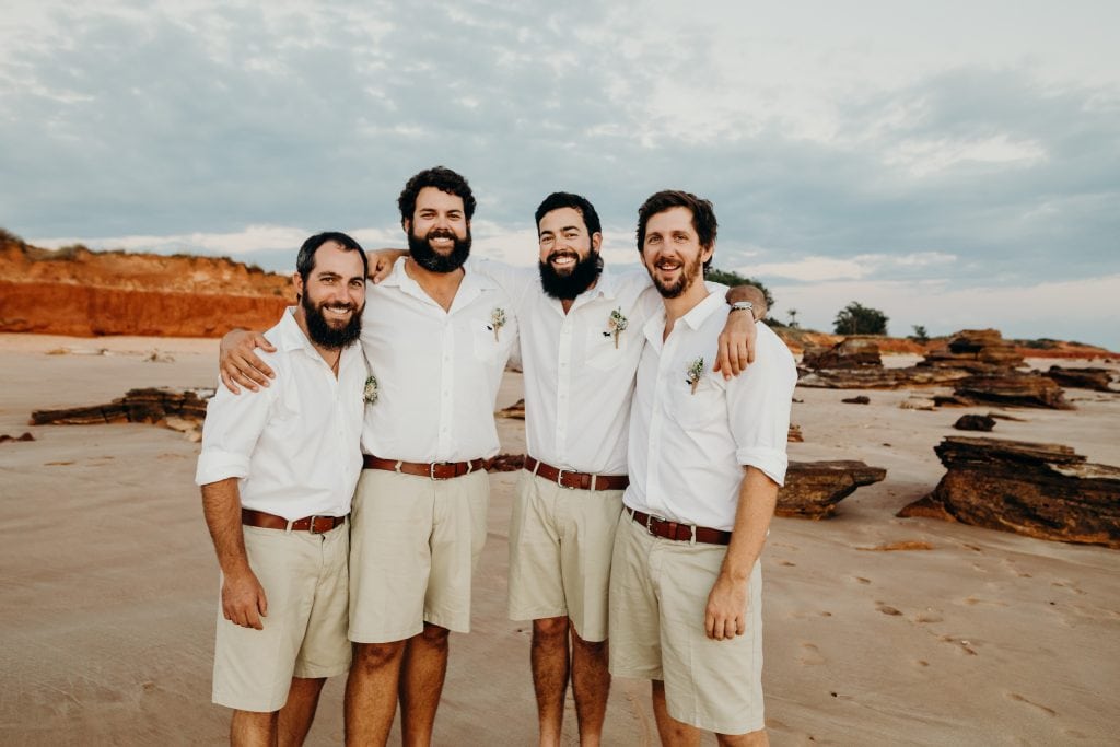 groom has his arms around his three groomsmen at Riddell Broome beach wedding 