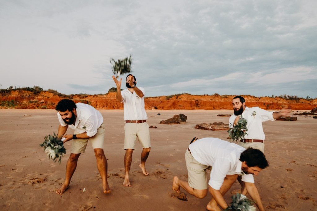 group of men jumping to catch flower bouquets at Broome beach wedding
