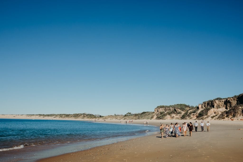 wedding guests walking along Eco Beach to ceremony location
