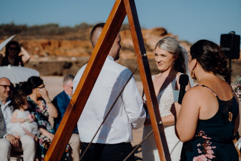 bride and groom facing each other during relaxed beach wedding at Entrance Point with celebrant holding microphone