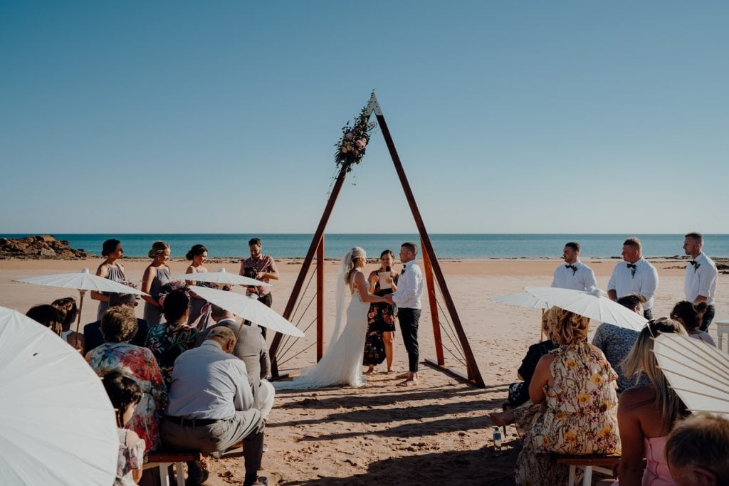 wedding ceremony set up with triangle arbour and ocean as backdrop