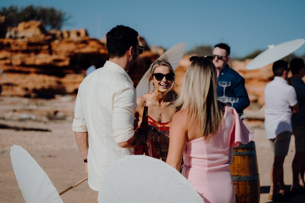 three people having an engaging conversation at beach wedding in Broome