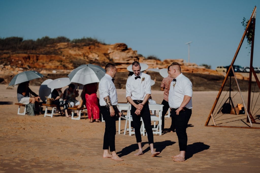 three young men in black pants and white shirts at beach wedding at Entrance Point