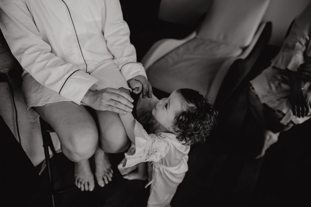 black and white photo of bride holding the hands of her little daughter during the getting ready