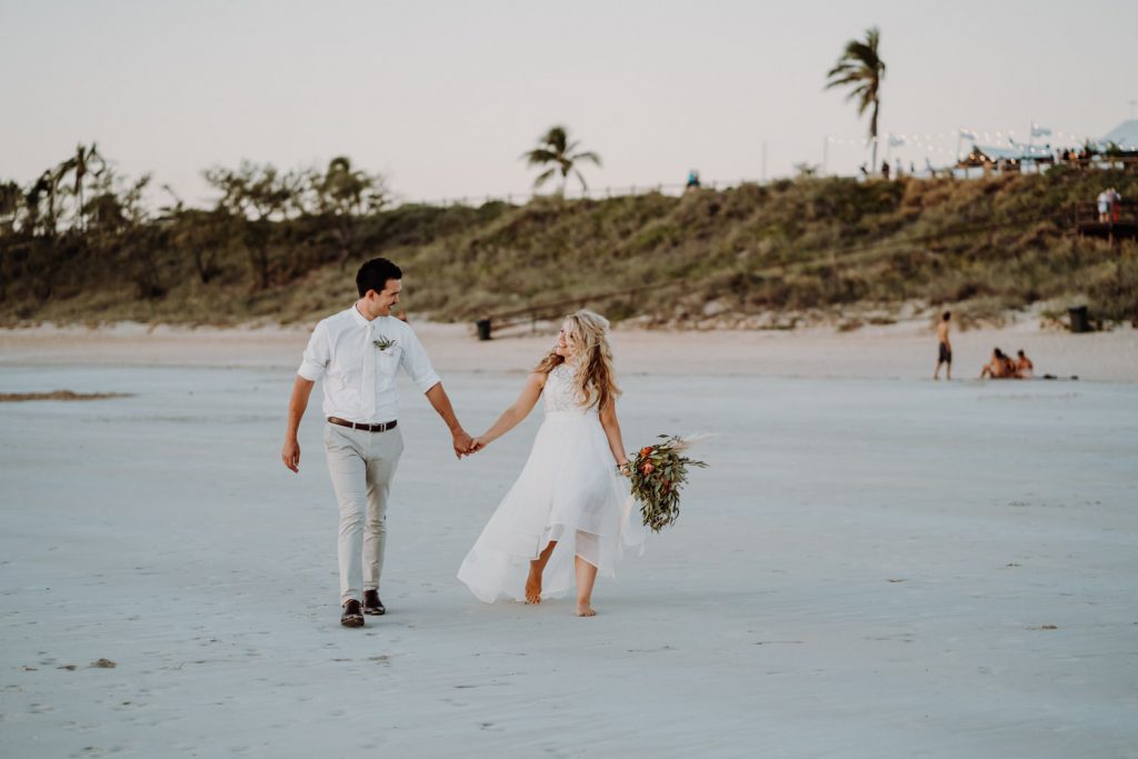 freshly married couple walks along Cable Beach in Broome