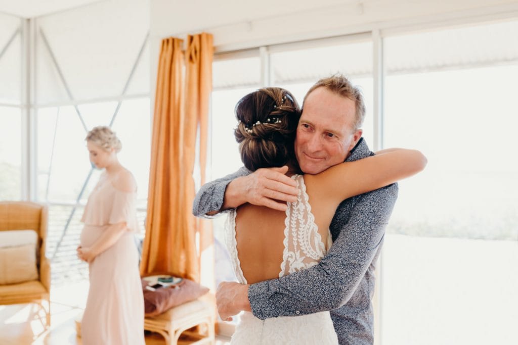 father of the bride gives his daughter a hug after seeing her in her wedding dress for the first time