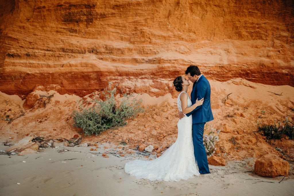 wedding couple standing in front of red pindan cliff 