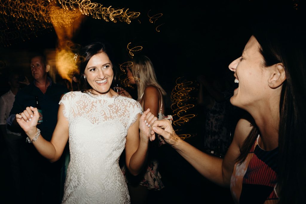 bride dancing with girlfriend on dancefloor at wedding
