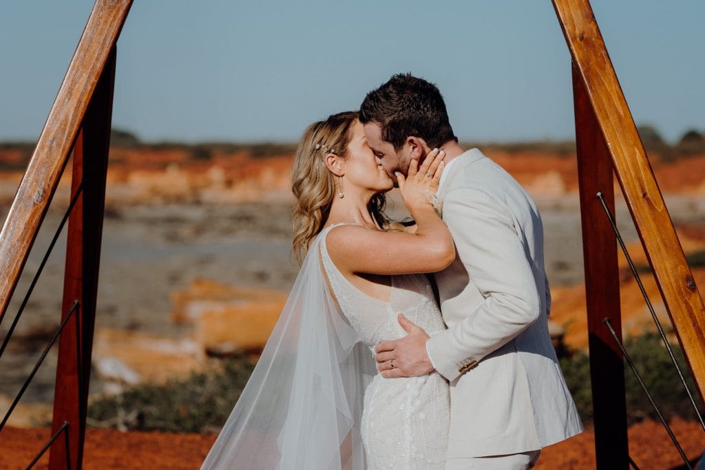first kiss as husband and wife for newlywed young couple at their wedding at Gantheaume Point